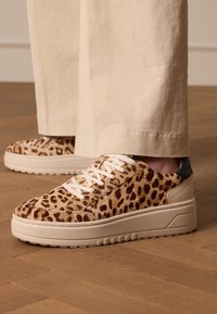 Leopardprint platform sneakers van textuur dierenhaar met witte veters en een crèmewitte rubberen zool, verfraaid met een donkere hieltab.
