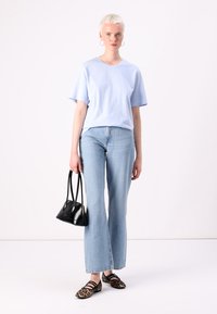 Light blue short-sleeve top, light blue flared jeans, black handbag, and animal-print flats. Simple design, soft textures, casual fit.