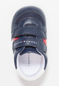 Námořnické modré kožené botičky pro batolata se suchými zipy. Obsahují bílé akcenty a červený design loga, zaoblenou špičku a měkkou vnitřní podšívku.