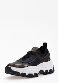 Chunky black sneakers with a textured leather upper, contrasting white sole, and gold accents. Features logo detail and lace-up design.