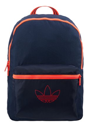 Sac à dos bleu marine avec fermeture éclair et bordure orange, poche avant avec logo rouge Adidas trefoil et poignée orange rayée.