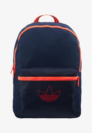 Sac à dos bleu marine avec fermeture éclair et bordure orange, poche avant avec logo rouge Adidas trefoil et poignée orange rayée.