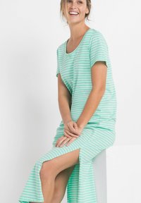 Abito righe verde menta con maniche corte, scollatura a barca e uno spacco laterale, realizzato in morbido cotone. Presenta strisce orizzontali bianche.