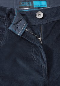 Námořnický kordurový materiál se zipem a knoflíkovým zapínáním. Obsahuje kontrastní tyrkysové švy a štítek s nápisem "CECI L WE LOVE PANTS."