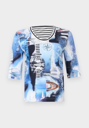 Chemise bleu à thème nautique avec des voiliers, un phare, une boussole et un bateau sur l'eau, avec un col rayé noir et blanc.