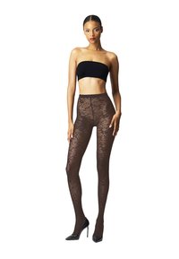 Donna in piedi con indosso un top nero senza spalline, collant neri trasparenti a motivi e scarpe col tacco nere su sfondo bianco.