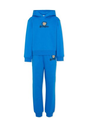 Jasnoniebieski zestaw dla dzieci: bluza z kapturem i spodnie dresowe z wizerunkami niedźwiadków oraz logo "Moschino" na piersi i udzie, widok z przodu na białym tle.