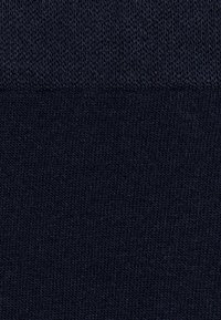 Granatowa bawełniana skarpetka z prążkowanym mankietem, prezentująca miękką, teksturowaną powierzchnię i delikatny, równomierny wzór dzianiny na całej długości.