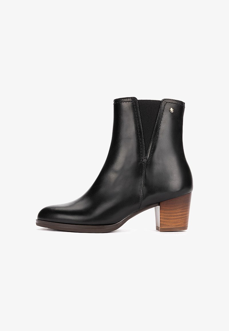 Bottine en cuir noir avec talon en bois empilé bas et panneaux latéraux élastiques pour un ajustement facile à enfiler.