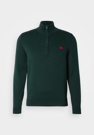 Tmavozelený pulóver so zipsom po polovici a rebrovanými manžetami a lemom. Na ľavej hrudi sa nachádza malé červené logo. Mäkký pletený materiál.