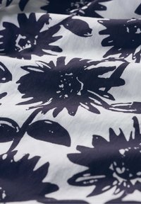 Baumwollstoff mit großen schwarzen Blumenmotiven auf weißem Hintergrund, mit einer glatten Textur und subtilen Variationen im Druck.