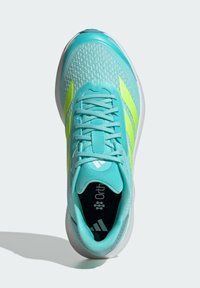 Light teal athletic shoe with mesh upper, neon yellow accents, flat laces, and a foam sole. Features Ortholite insole branding inside.