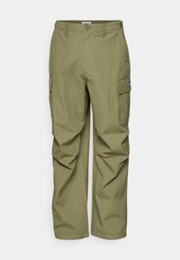 Cargo pants in light olive green, featuring multiple side pockets, a button closure, and a relaxed fit. Made from textured fabric.