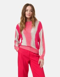 Rosa Pullover mit weißem Zickzackmuster, strukturiertem Strick sowie gerippten Bündchen und Saum, kombiniert mit leuchtend rosa Hosen.