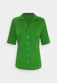 Camicia verde a maniche corte realizzata in tessuto morbido, dotata di chiusura con bottoni, colletto e sottili cuciture verticali per una vestibilità su misura.