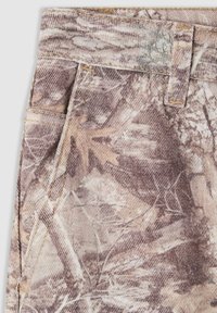 Tessuto a motivo camouflage con tonalità di marrone e beige. Presenta linee nette, una superficie testurizzata e cuciture visibili su tasche e cintura.