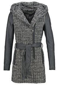 Schwarze und weiße gemusterte Jacke; strukturierter Stoffkörper mit langen Lederärmeln; Frontreißverschluss und Gürteldetails; Kapuzen design.