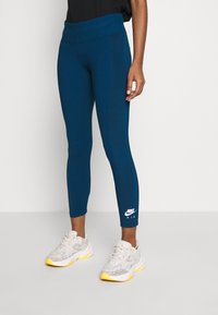 Blå tajta leggings med bred midja och Nike Air-logotyp vid vristerna, kombinera med ljusa träningsskor.