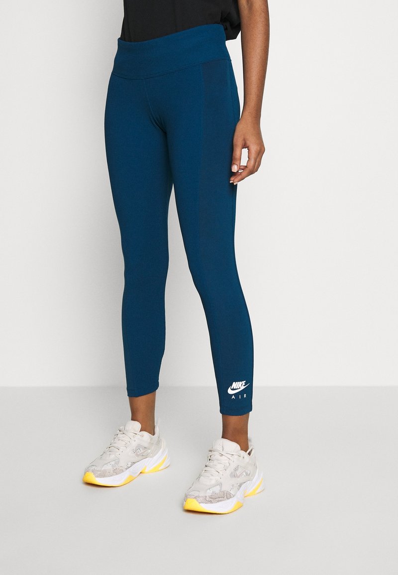 Blå tajta leggings med bred midja och Nike Air-logotyp vid vristerna, kombinera med ljusa träningsskor.