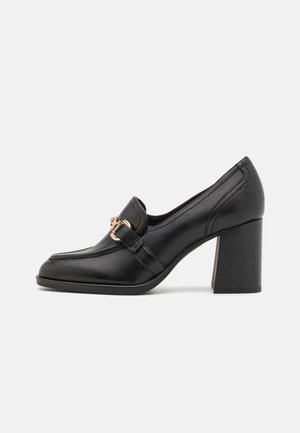 Black leather high-heeled shoe with a rounded toe, decorative buckle strap, and a chunky block heel. Smooth texture and sleek design.