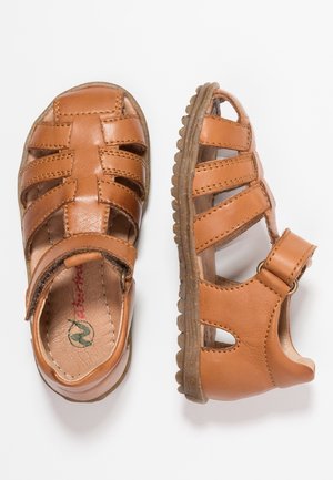 Sandali in pelle marrone chiaro per bambini piccoli, chiusi sulle punte, con cinturini regolabili alla caviglia e suole in gomma imbottite, mostrati da viste dall'alto e di lato.