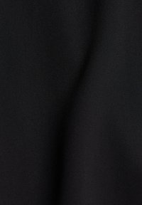 Gros plan sur un tissu noir avec une texture fine et des plis subtils créant des variations de lumière et d'ombre.