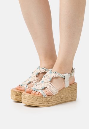 Platform sandalen met een geweven tan en lichtblauwe macramé bovenkant, voorzien van een band en enkelgesp, en een gestructureerde kurken wedge zool.
