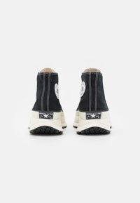 Baskets montantes en toile noire avec des coutures blanches, semelles en caoutchouc et logo Converse au talon. Dispose d'une semelle extérieure en caoutchouc texturé.