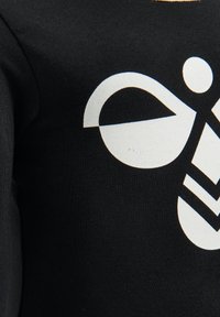 Zwarte stoffen t-shirt met een grote witte grafische ontwerp, inclusief cirkelvormige en driehoekige vormen, met een gladde structuur.