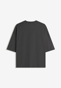 Dark gray oversized T-shirt made from soft fabric. Short sleeves, round neck, and a clean, seamless back design. No visible logos or patterns.