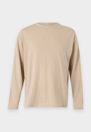 Beige langermet skjorte laget av mykt stoff med rett snitt, rund halsutskjæring og minimale søm detaljer langs nederkant og ermer.