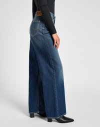 Wide-leg blue denim jeans with a high waist, featuring contrast stitching and a brown leather back patch with logo. Smooth texture, casual fit.