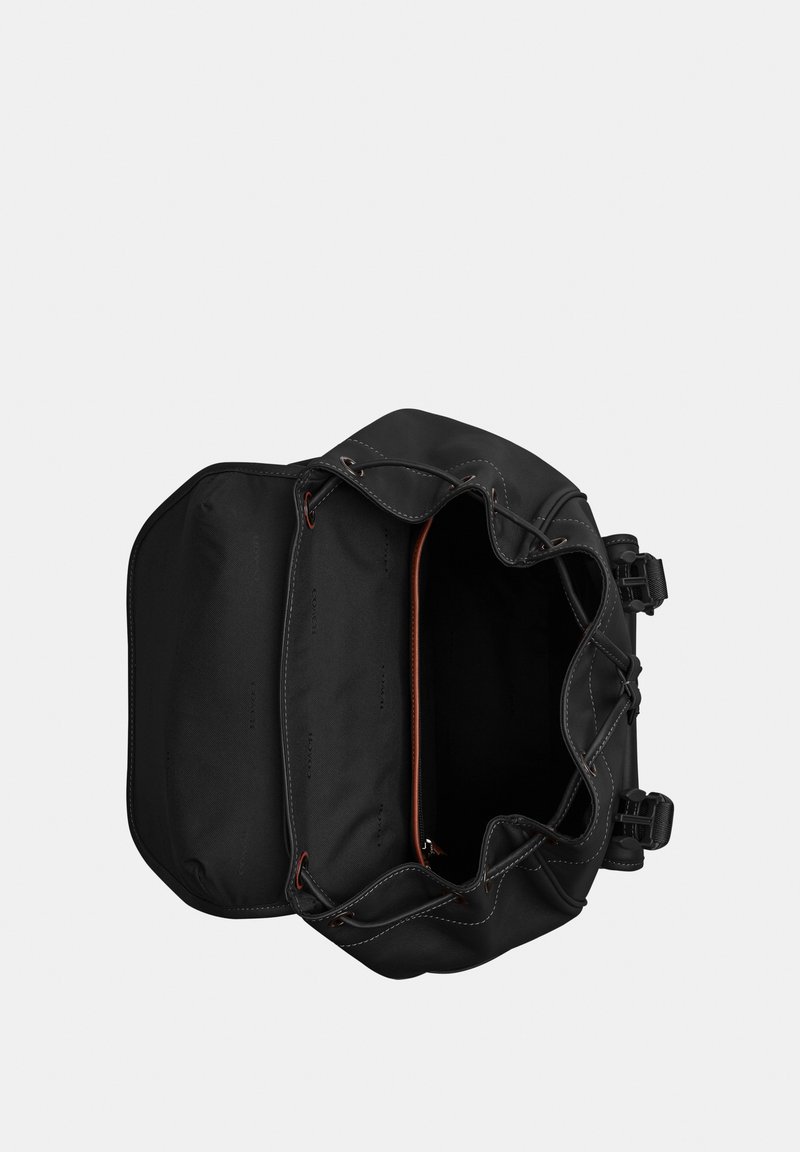 Mochila negra abierta con cierre de cordón y solapa, mostrando un compartimento principal espacioso y un bolsillo interno con cremallera.