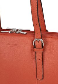 Borsa a mano in pelle arancione con superficie texture, dotata di doppia cerniera, hardware argento e tracolla removibile. Logo impresso sulla borsa.