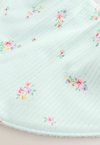 Vaaleansininen kangas, jossa on hienoa pystysuoraa ribbineulosta ja pieniä hajallaan olevia ryhmiä vaaleanpunaisia, keltaisia ja purppuranvärisiä kukkia vihreine lehtineen.