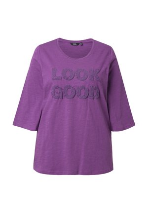 Lila T-Shirt mit kurzen Ärmeln und rundem Ausschnitt, mit erhabenen Schriftzug "LOOK GOOD" in dunklerem Lila auf einem strukturierten Stoff.