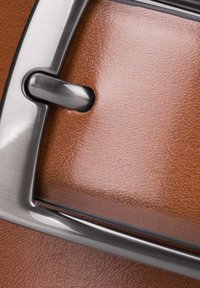 Brązowa skórzana faktura z metalową klamrą w kolorze srebrnym. Powierzchnia ma ziarnisty wzór, co zwiększa atrakcyjność dotykową i wizualne zainteresowanie.