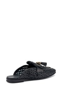 Sandalo scivoloso intrecciato nero con una tomaia testurizzata, dettaglio con nappina e accenti in pelle, suola piatta e lati aperti per traspirabilità.
