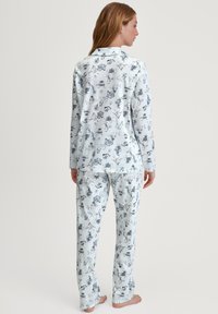 Lichtblauw pyjamapak van zachte stof, met een all-over print van verschillende winterthemed illustraties. Lange mouwen, relaxte pasvorm.