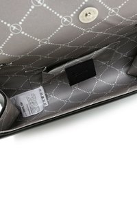 Interno di una borsa nera con rivestimento a motivo grigio. Presenta una chiusura a scatto sicura e molteplici tasche per l'organizzazione. Etichetta per la cura inclusa.