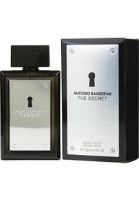 Eau de Toilette mustassa suorakulmaisessa lasipullossa, jossa on hopeinen metallilaatta, jossa on avaimenreikäkuvio. Rikkinäinen pakkaus on musta hopeisilla yksityiskohdilla.