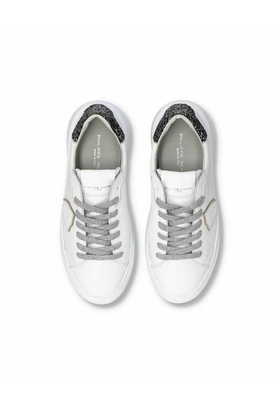 Een paar witte lage sneakers met grijze veters en zwarte, gestructureerde hielstukjes, gezien van boven op een witte achtergrond.