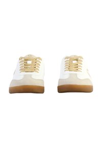 Baskets blanches avec un bout en daim beige, des lacets dorés et une semelle en gomme. Le design comporte un détail de logo sur la languette et sur les côtés.