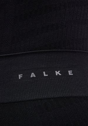 Leggings neri a maglia con una texture a coste. Presentano una vita ampia con la scritta "FALKE" stampata in grigio. Tessuto dalla finitura liscia, senza motivi visibili.