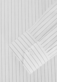 Witte overhemd met zwarte verticale strepen, voorzien van een knoopmanchet en een gladde, gestructureerde stof. Klassieke kraagstijl, op maat gesneden pasvorm.