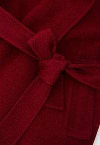 Roter Wollmischungsmantel mit Bindegurt, weichem Textil und Reverskragen. Enthält gestickte Details und eine Seitentasche.