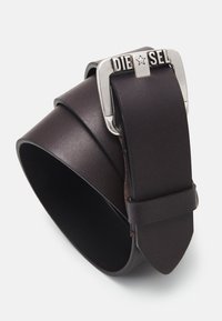 Cinturón de piel marrón con acabado mate, que presenta una hebilla rectangular de plata embellecida con "DIESEL". Textura lisa y punta tapered.