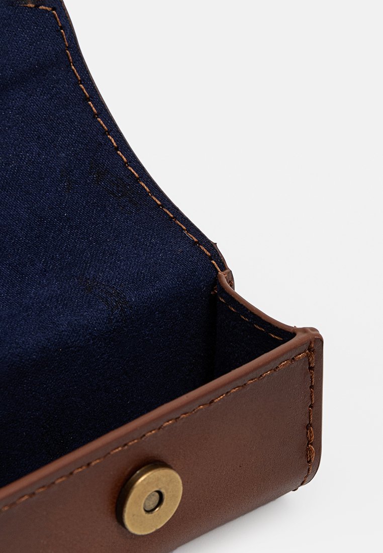 Vassoio in pelle marrone con bottone a pressione in ottone e rivestimento in tessuto blu navy, che mostra dettagliati cuciture e costruzione degli angoli.