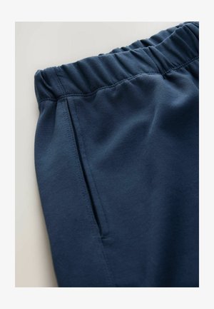 Granatowe dresy z elastycznym paskiem w talii i boczną kieszenią. Wykonane z miękkiego, teksturowanego materiału z detalicznym zszywaniem.