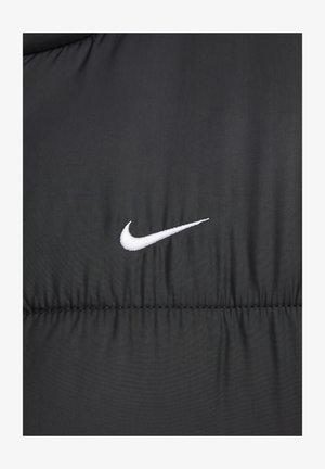Juodas pūkuotas švarkas su siuvinėtu raštu ir balta siuvinėta Nike logotipu kairėje pusėje. Pagamintas iš lygios, sintetinės medžiagos.